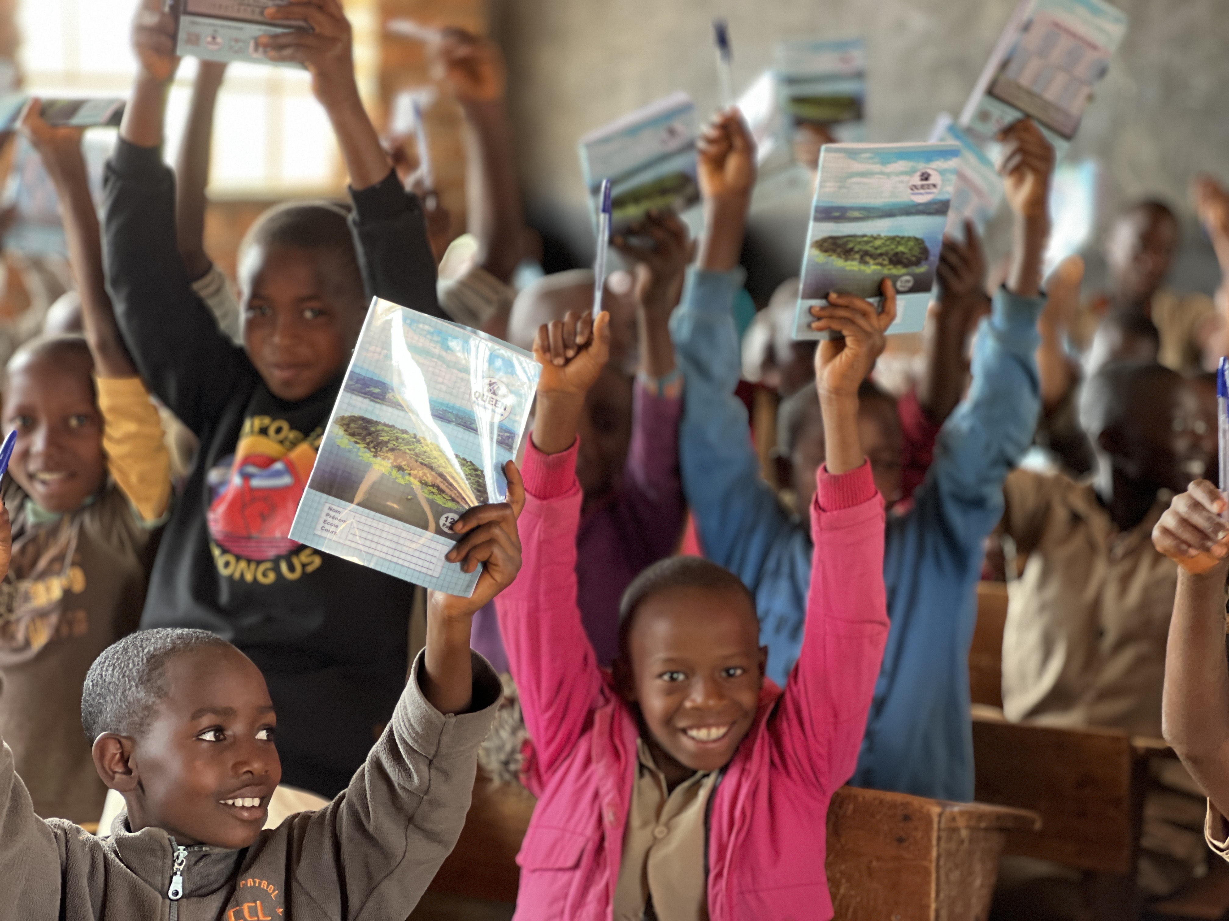 Kids holding new notebooks at Discovery School Kibuye